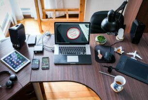 A contemporary office desk setup with laptops, gadgets, and accessories, creating a tech-savvy workplace.