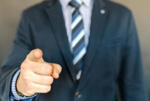 A businessman in a dark suit points forward, emphasizing focus and professionalism.