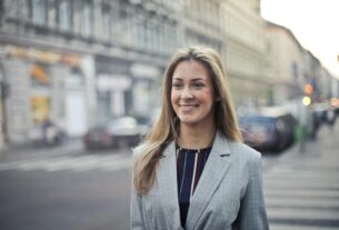 Confident businesswoman smiling outdoors in urban Budapest setting.